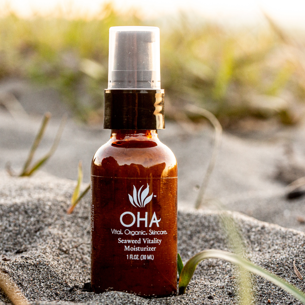 Bottle of rejuvenating moisturizer made with seaweed extracts surrounded by sand 