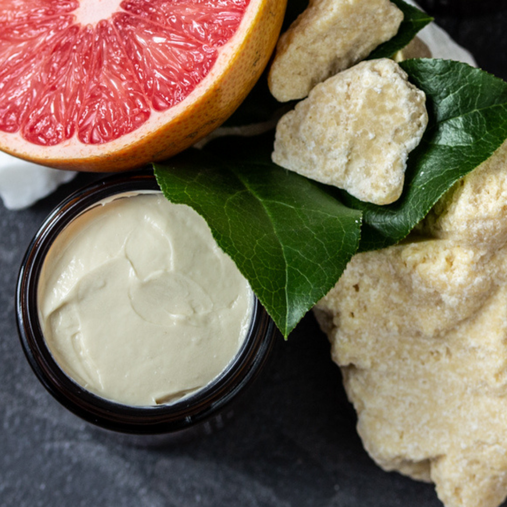 Face cream with vitamin c orange and rosehip in a glass jar surrounded by grapefruit and green leaves