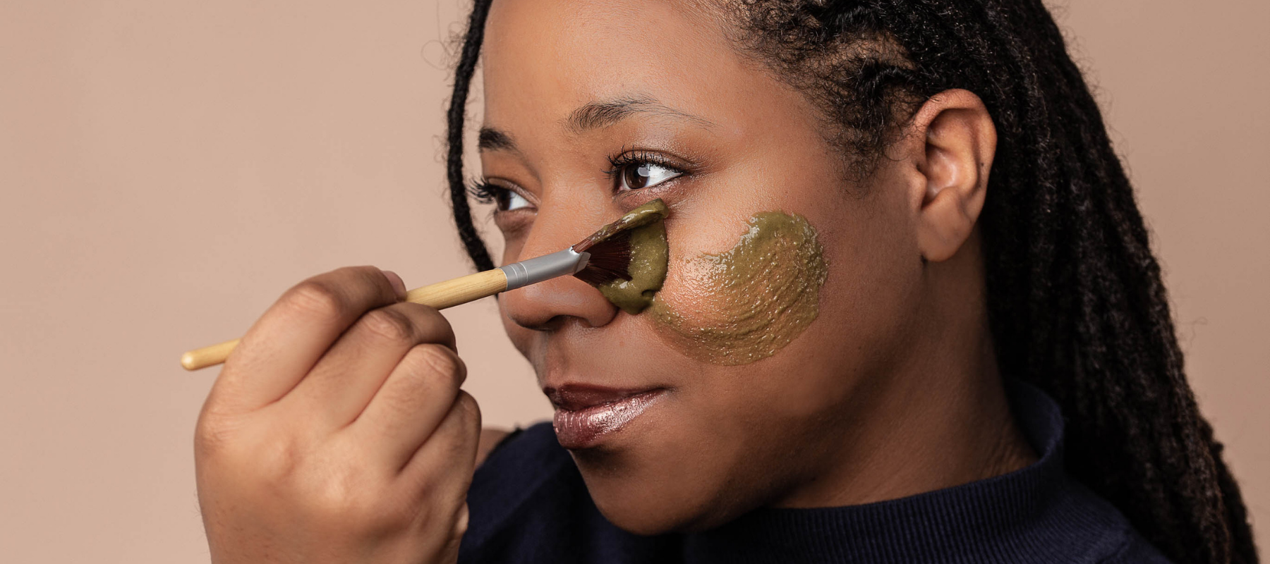 Woman applying all-natural face mask to skin with bamboo brush
