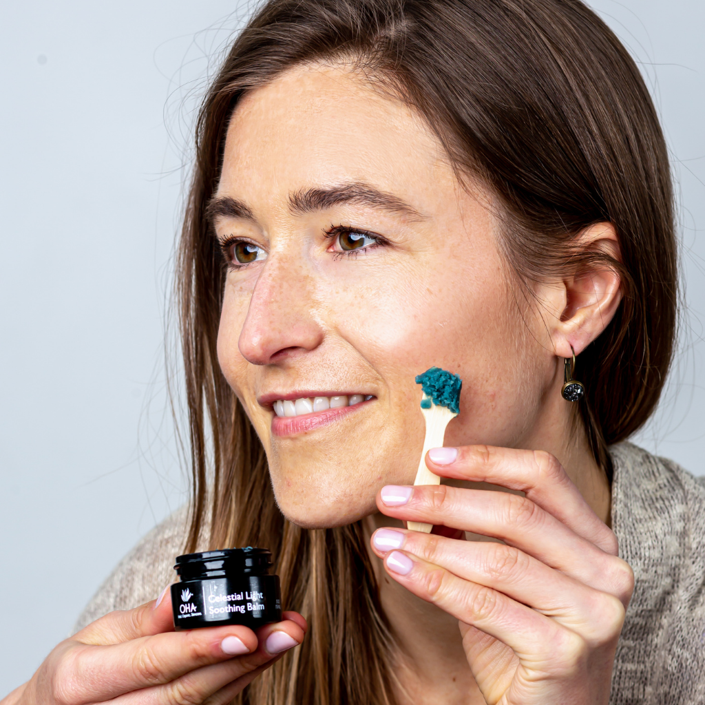 Woman applying blue soothing facial balm to face