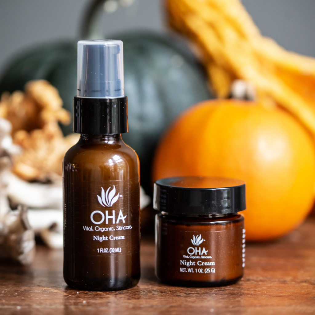 Glass jar and bottle of organic night cream for face shown with pumpkins