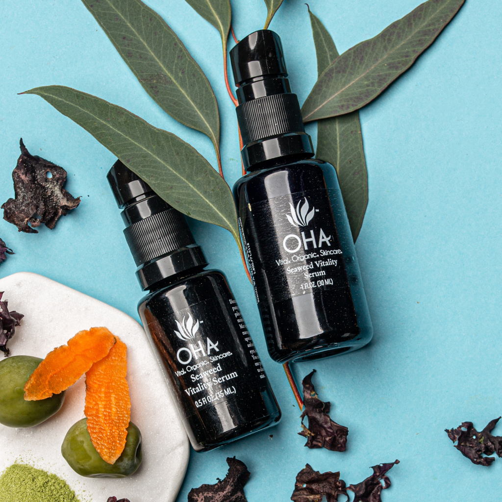 Bottles of firming facial serum made with seaweed surrounded by vibrant natural ingredients
